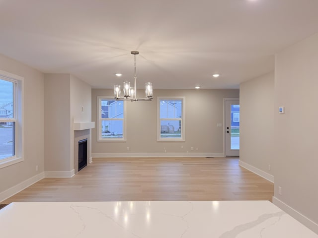 unfurnished living room with a notable chandelier and light hardwood / wood-style floors