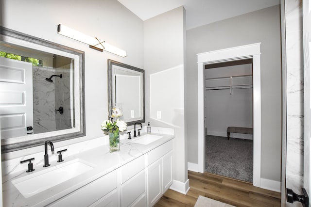 bathroom with tiled shower, vanity, and hardwood / wood-style flooring