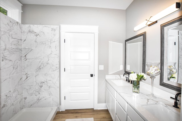 bathroom featuring hardwood / wood-style flooring, vanity, and tiled shower