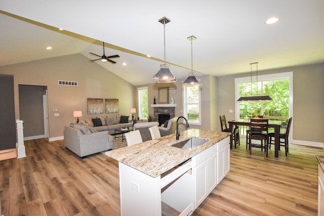 kitchen with white dishwasher, ceiling fan, a kitchen island with sink, sink, and white cabinets