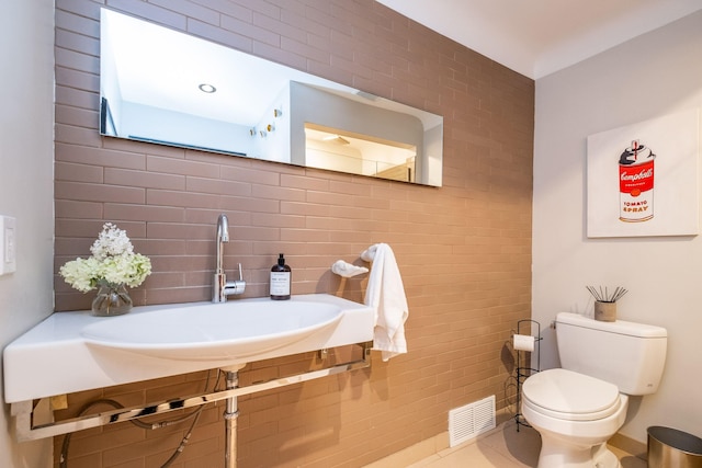 bathroom featuring tile patterned floors, toilet, tile walls, and sink