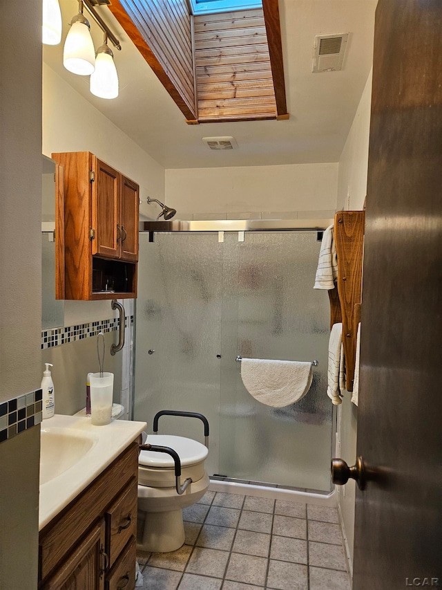 bathroom with vanity, a skylight, toilet, tasteful backsplash, and an enclosed shower