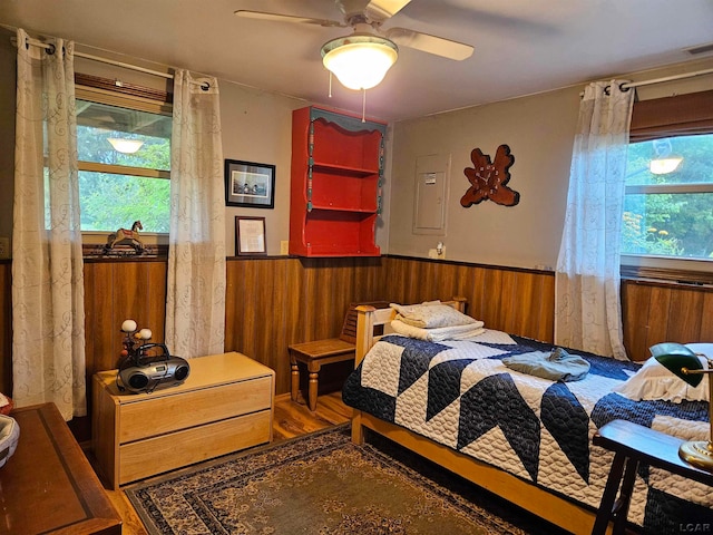 bedroom featuring wood-type flooring, ceiling fan, and wood walls