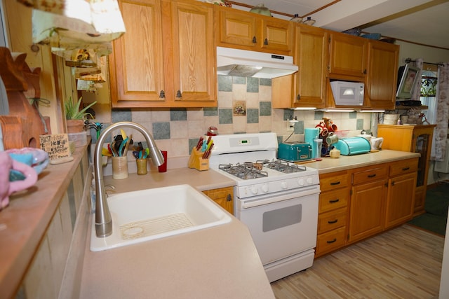 kitchen with decorative backsplash, light hardwood / wood-style floors, white appliances, and sink