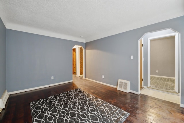 spare room with a textured ceiling and hardwood / wood-style flooring