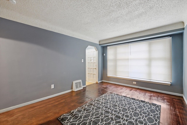 unfurnished room with dark hardwood / wood-style flooring and a textured ceiling