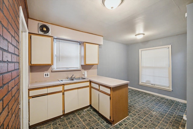 kitchen featuring kitchen peninsula, brick wall, and sink