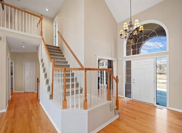 entryway with high vaulted ceiling, a notable chandelier, and light wood-type flooring