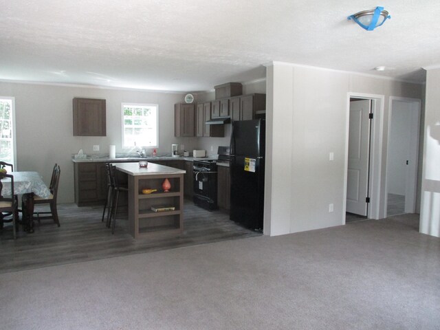 kitchen featuring black appliances, sink, a textured ceiling, a kitchen island, and a breakfast bar area