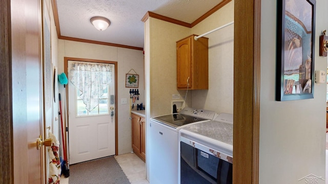 laundry area with washing machine and clothes dryer, crown molding, cabinets, and a textured ceiling