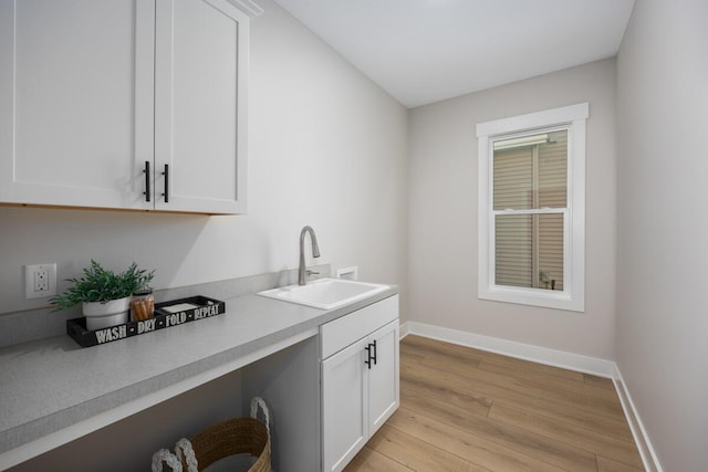 interior space with white cabinets, plenty of natural light, sink, and light hardwood / wood-style flooring