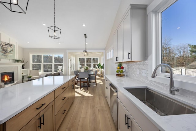 kitchen with light stone countertops, white cabinetry, sink, and hanging light fixtures