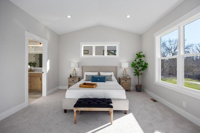 carpeted bedroom featuring ensuite bathroom and vaulted ceiling