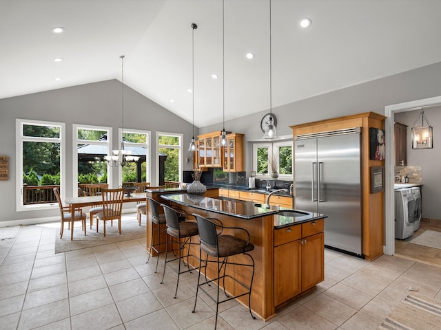 kitchen with vaulted ceiling, sink, stainless steel built in fridge, washer / dryer, and a kitchen island