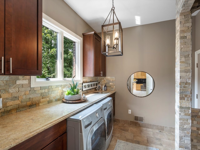 clothes washing area featuring a chandelier, washer and clothes dryer, and sink