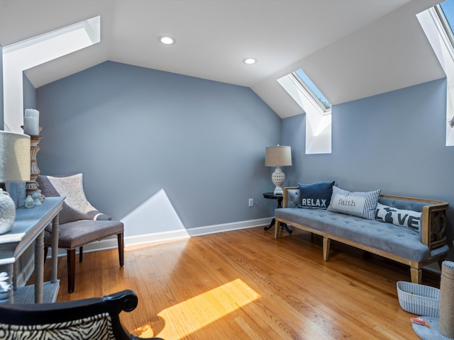 living area with lofted ceiling with skylight and hardwood / wood-style flooring