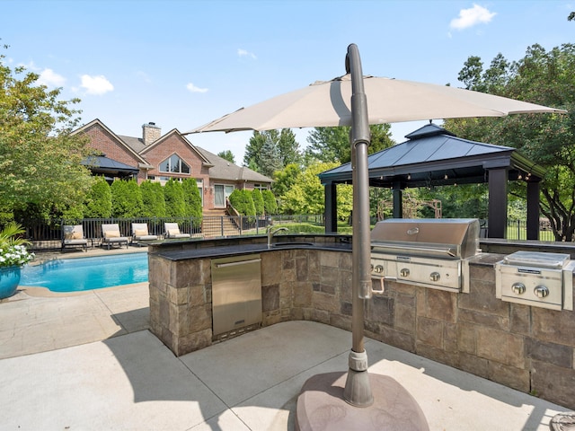 view of swimming pool with an outdoor kitchen, a gazebo, pool water feature, a grill, and a patio