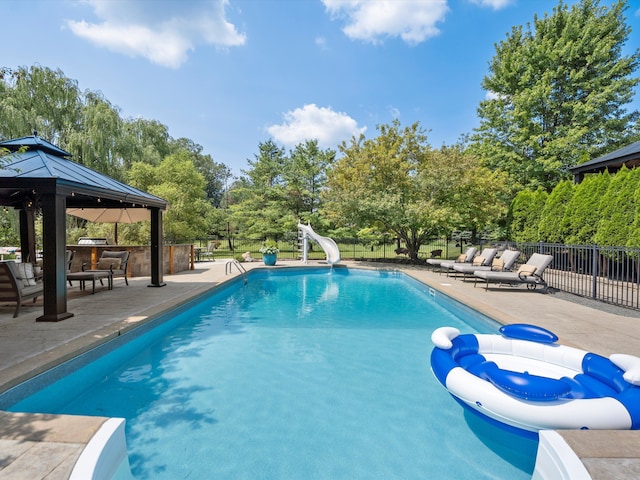 view of swimming pool featuring a gazebo, a patio, an outdoor bar, and a water slide