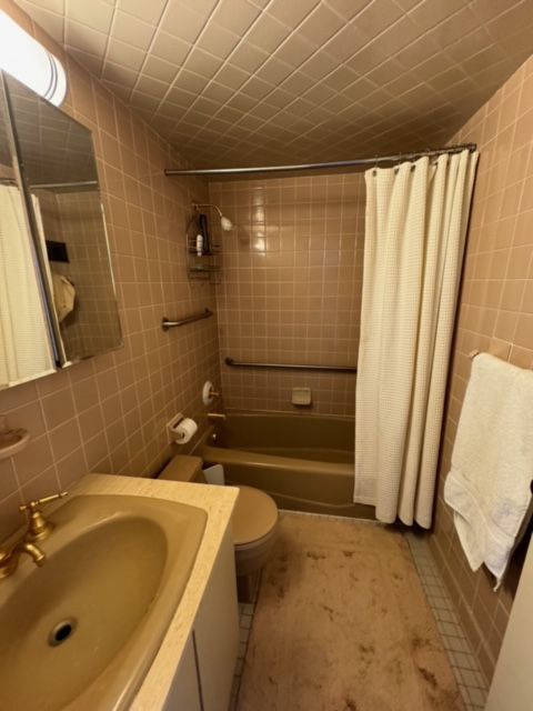 full bathroom with tile patterned floors, shower / bath combo with shower curtain, sink, tile walls, and toilet