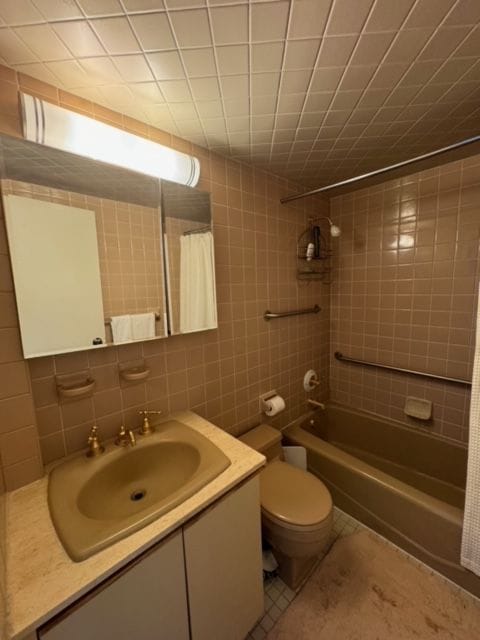 full bathroom with shower / bath combo, tasteful backsplash, vanity, tile walls, and toilet