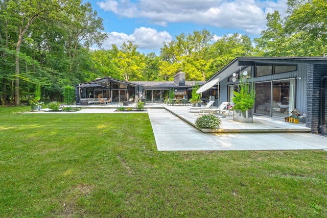 back of property with a lawn, glass enclosure, and a patio area