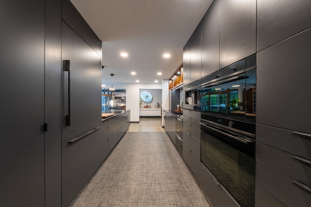 kitchen featuring hanging light fixtures, black oven, and stainless steel built in fridge