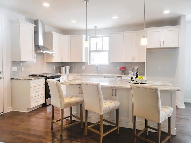 kitchen with white cabinets, a kitchen island, wall chimney range hood, and appliances with stainless steel finishes