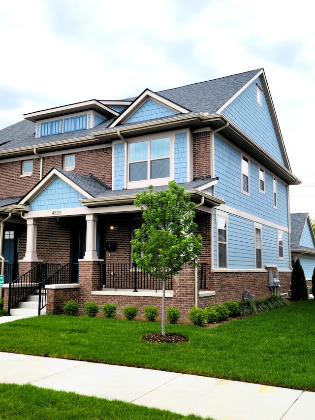 craftsman inspired home featuring covered porch and a front yard