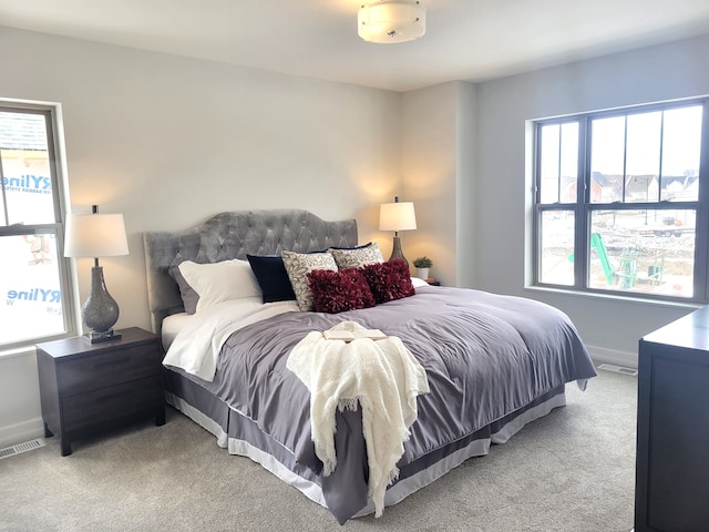 bedroom with light carpet and multiple windows