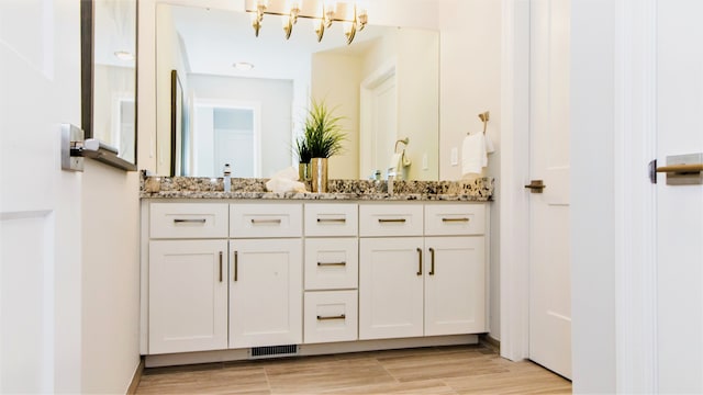 bathroom with hardwood / wood-style floors, vanity, and a chandelier