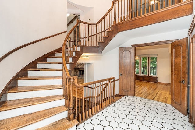 staircase with a towering ceiling and hardwood / wood-style flooring