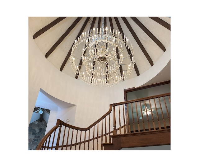 stairs with a notable chandelier and a towering ceiling