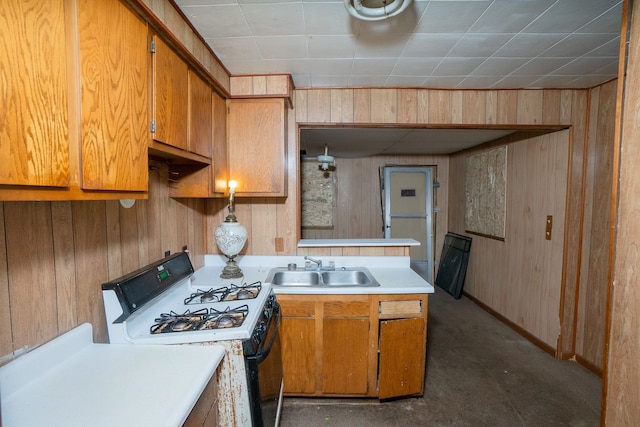 kitchen with white gas stove, sink, and wooden walls