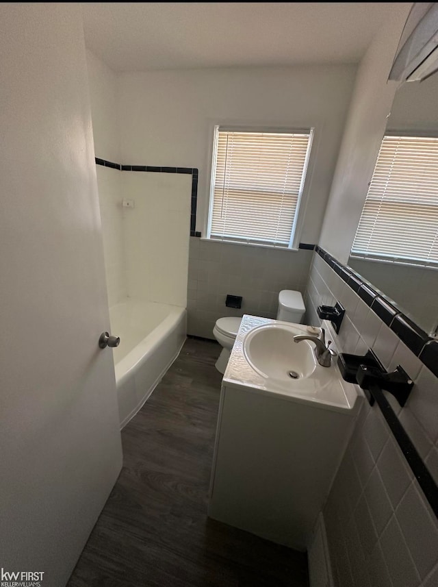 bathroom featuring hardwood / wood-style floors, vanity, toilet, and tile walls