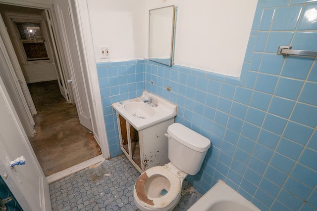 bathroom featuring tile patterned floors, vanity, tile walls, toilet, and a bathing tub