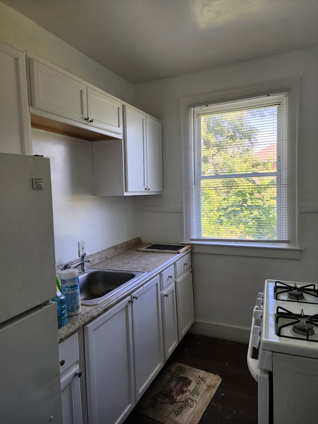 kitchen featuring refrigerator, white cabinetry, white gas range, and sink