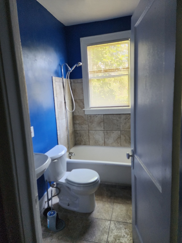 bathroom with tile patterned flooring, tiled shower / bath combo, and toilet