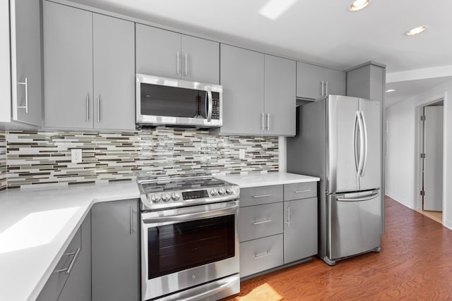 kitchen featuring gray cabinetry, tasteful backsplash, light hardwood / wood-style floors, and appliances with stainless steel finishes