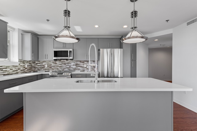 kitchen featuring an island with sink, appliances with stainless steel finishes, and gray cabinetry