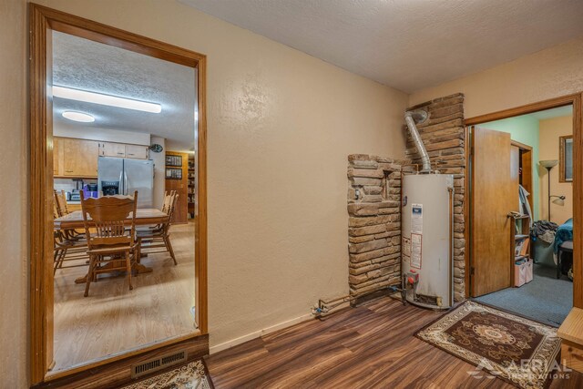4100 Grass Lake Rd, West Branch, MI 48661 - corridor featuring gas water heater, wood finished floors, a textured ceiling, a textured wall, and baseboards