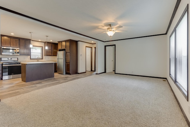 kitchen with appliances with stainless steel finishes, ceiling fan, sink, pendant lighting, and a center island