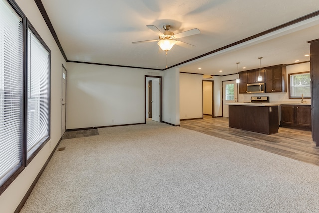 unfurnished living room featuring light hardwood / wood-style flooring, ceiling fan, crown molding, and sink