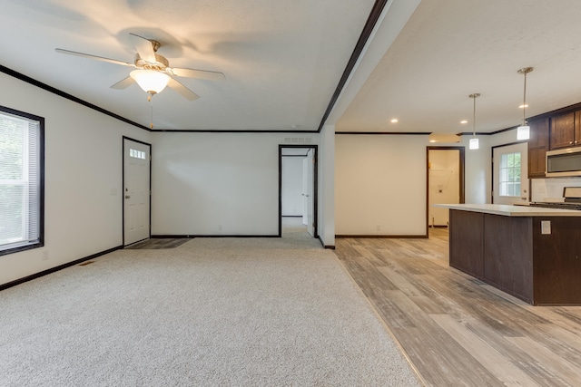 unfurnished living room featuring light wood-type flooring, plenty of natural light, crown molding, and ceiling fan