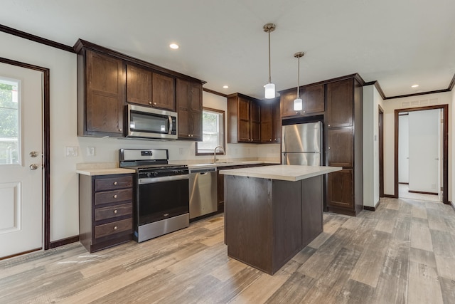 kitchen featuring appliances with stainless steel finishes, light wood-type flooring, decorative light fixtures, and a center island