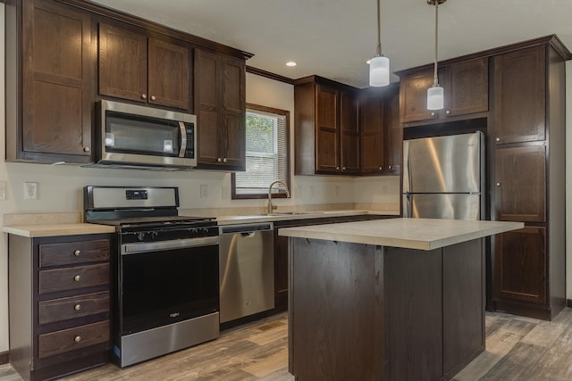 kitchen with light hardwood / wood-style flooring, stainless steel appliances, decorative light fixtures, and sink