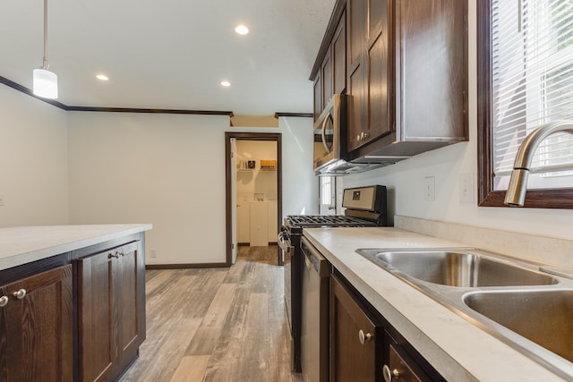 kitchen with appliances with stainless steel finishes, ornamental molding, sink, pendant lighting, and light hardwood / wood-style flooring