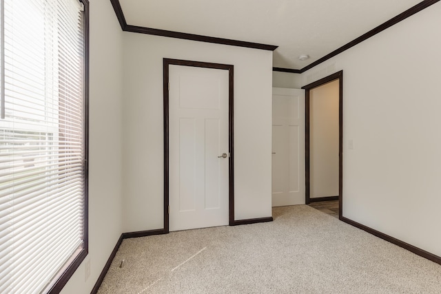 unfurnished bedroom with crown molding and light colored carpet