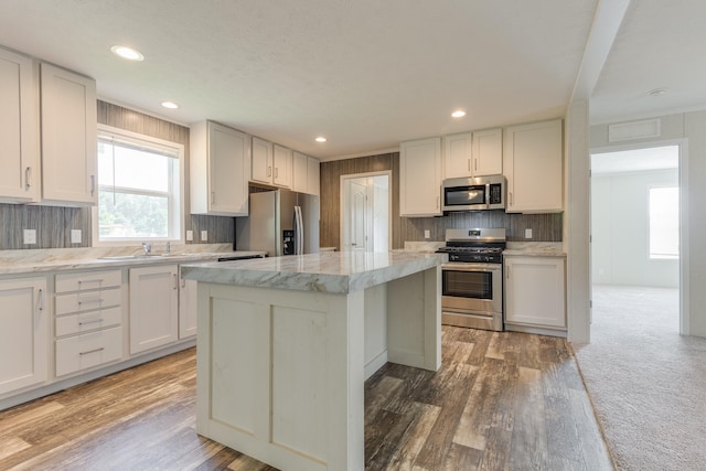 575 Gallery Dr Unit 48, Eaton Rapids, MI 48827 - kitchen featuring appliances with stainless steel finishes, decorative backsplash, a kitchen island, light wood finished floors, and recessed lighting