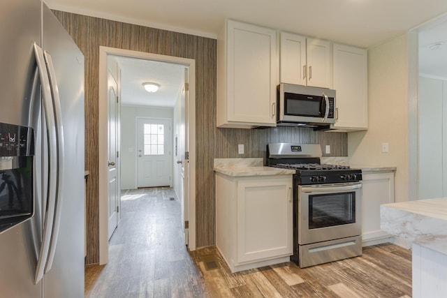 575 Gallery Dr Unit 48, Eaton Rapids, MI 48827 - kitchen featuring appliances with stainless steel finishes, light wood finished floors, white cabinets, and light stone countertops