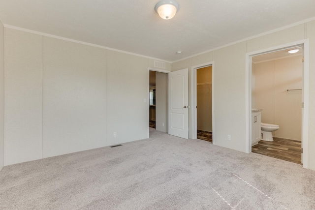 575 Gallery Dr Unit 48, Eaton Rapids, MI 48827 - unfurnished bedroom with carpet floors, crown molding, a walk in closet, connected bathroom, and a closet